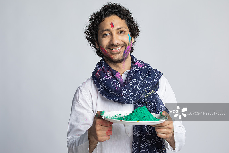 兴奋的年轻人手持五彩粉末，背景为白色图片素材