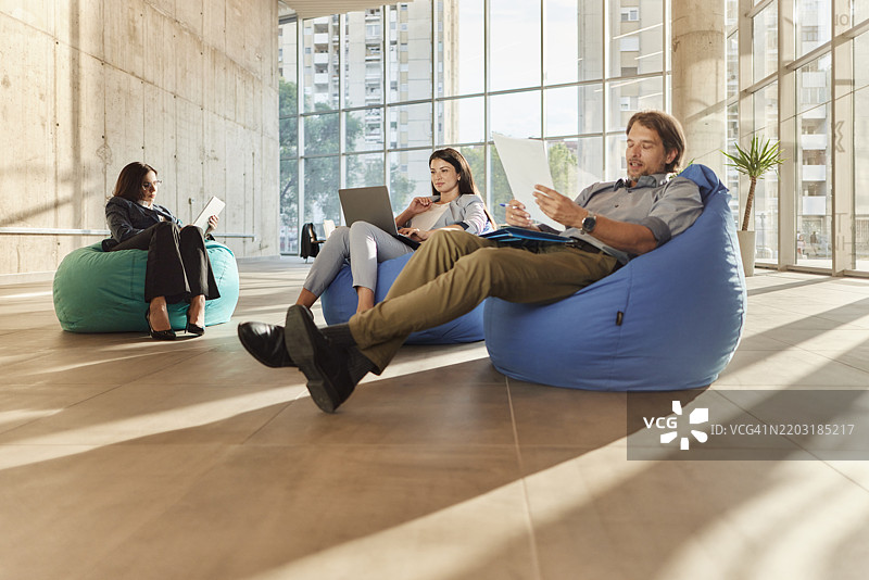 商务同事在休闲办公室里使用电脑和处理文件。图片素材