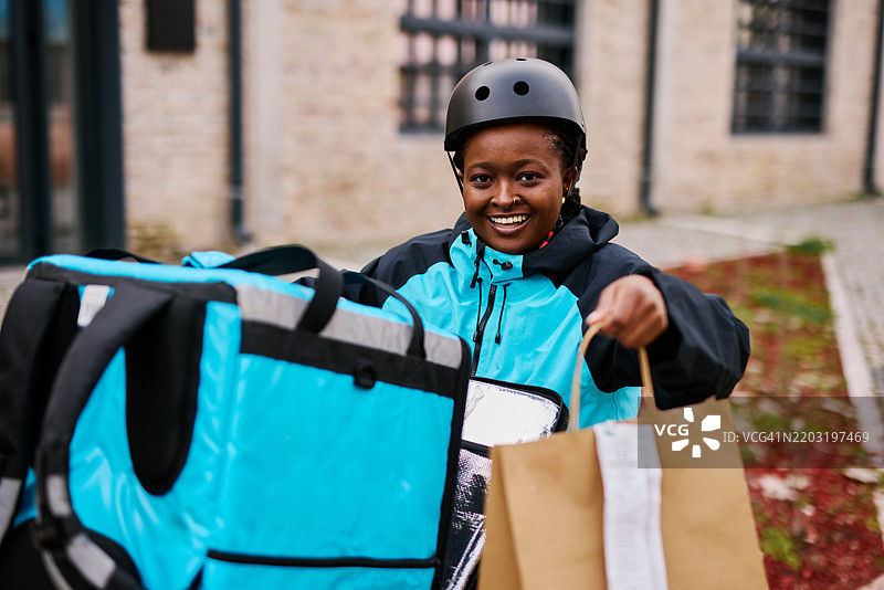 微笑的送餐员手持食品袋和保温背包送货图片素材