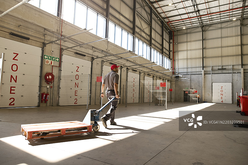 仓库工人推着空手推车走动图片素材