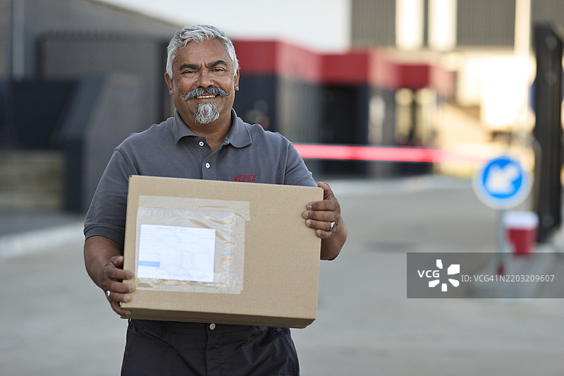 快乐的老年快递员站着手持纸箱图片素材