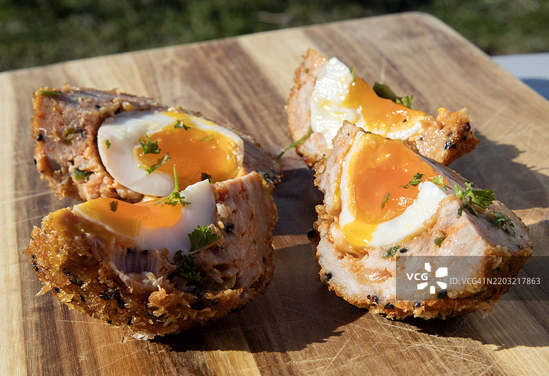 特写的手工泡菜和猪肉苏格兰蛋，旁边放着香菜，背景为木质桌面图片素材