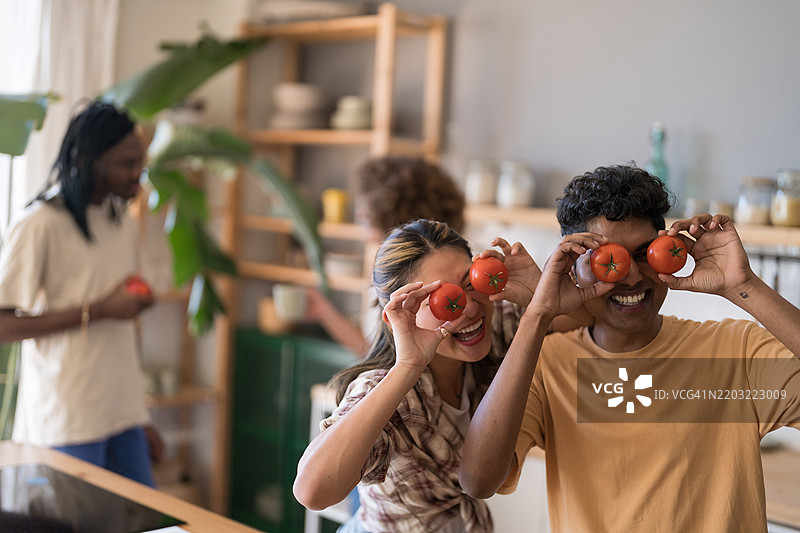 快乐的情侣在厨房里玩番茄图片素材