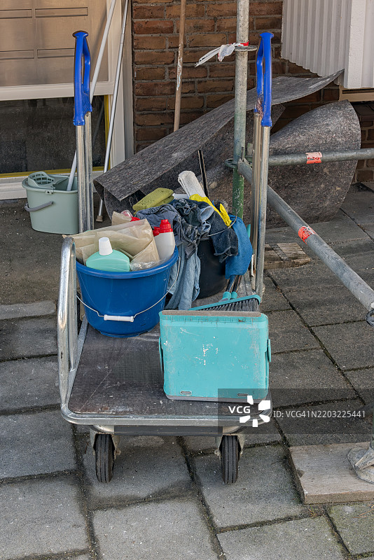 清洁车上有各种清洁工具，停在 sidewalk 上。图片素材