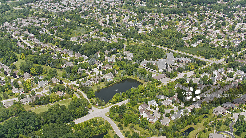 密歇根州兰辛郊区郁郁葱葱的社区，绿树成荫，池塘环绕图片素材