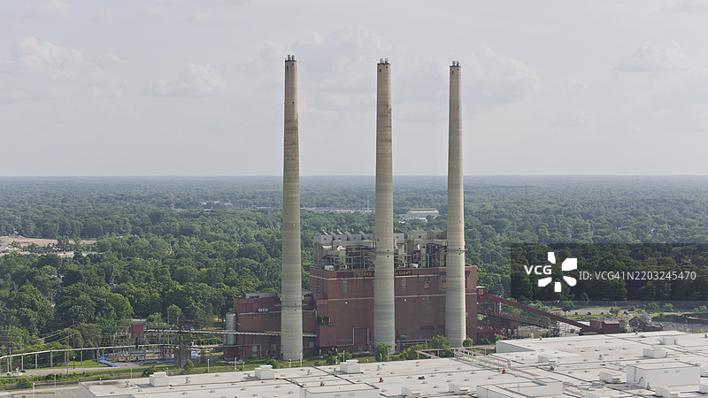 工业烟囱高耸于密歇根州兰辛的树冠之上图片素材