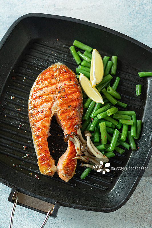 烤三文鱼排，烤鳟鱼配青豆、香菇和柠檬，放在烤盘中。图片素材