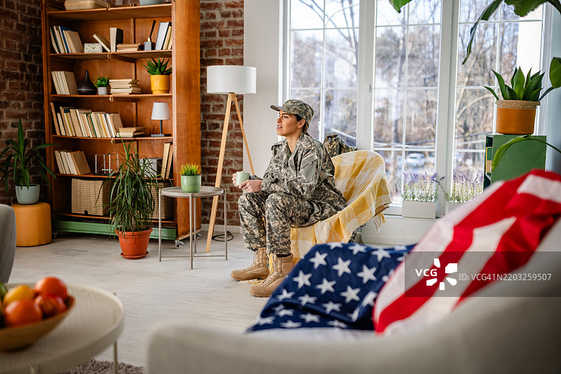 年轻女性穿着军装，在舒适现代的客厅环境中悠闲地享用咖啡图片素材