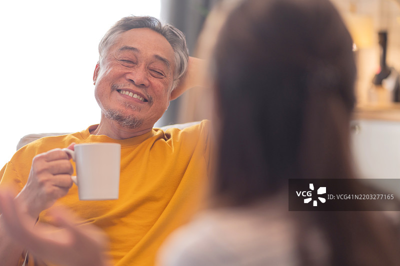居家生活，老年生活方式概念。亚洲老年父母和女儿在家中一起度过闲暇时光，快乐的家庭在沙发上放松。图片素材