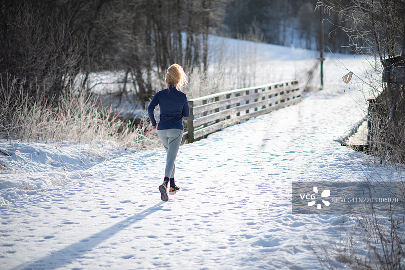 时尚女性穿着健身服在户外慢跑的背影。图片素材