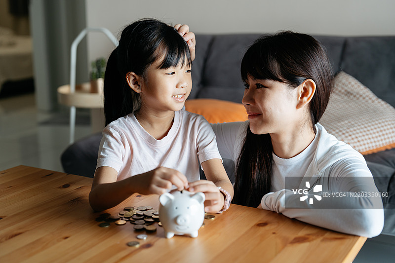 亚洲母女正在往储蓄罐里投硬币图片素材