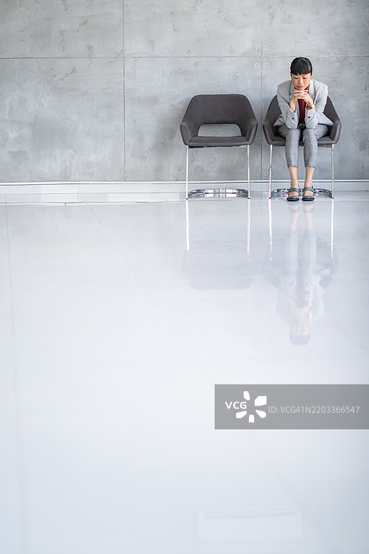 紧张的女商人在现代办公室内坐着图片素材