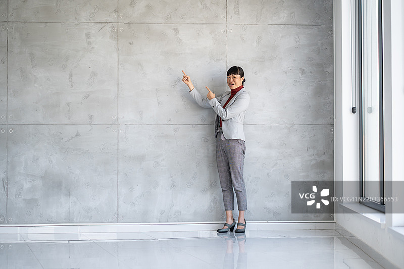 自信的职业女性指着墙面展示。图片素材