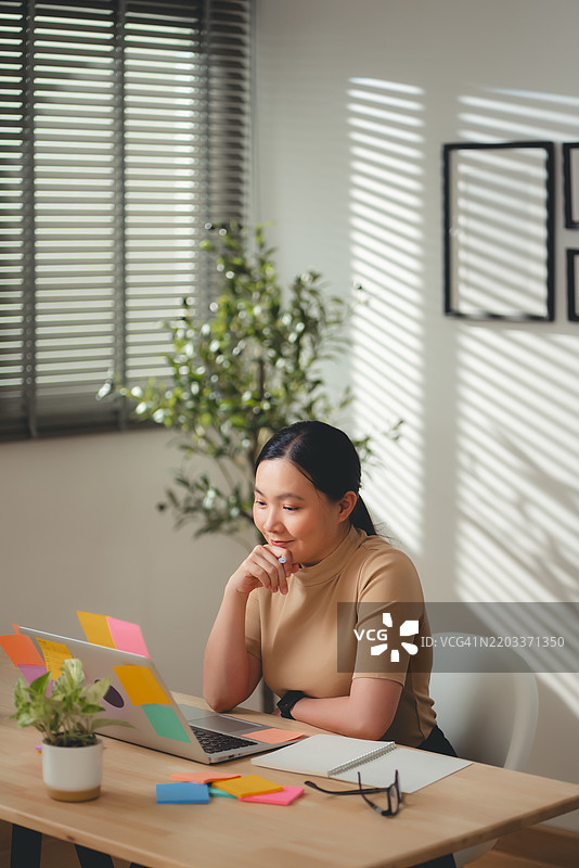 亚洲女性在家办公时享受工作和记录新想法。图片素材