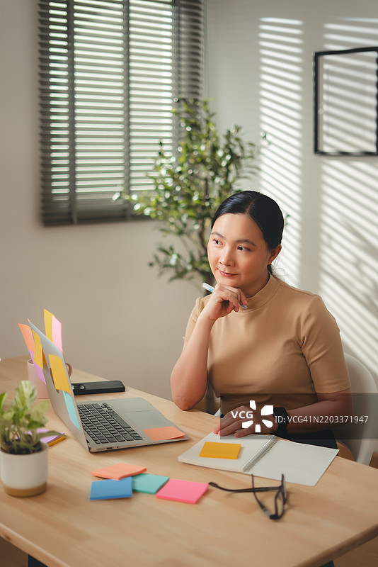 亚洲女性在家办公室享受工作和记录新想法。图片素材