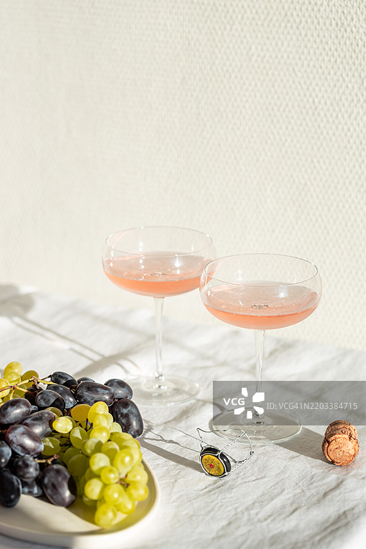 静物画：两杯玫瑰香槟和一盘葡萄。图片素材