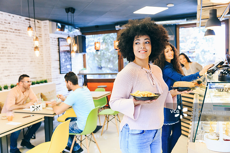 非洲女性手里端着装有三明治和薯条的盘子图片素材