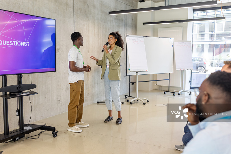 女性商业演讲者在研讨会上与男性参与者互动图片素材