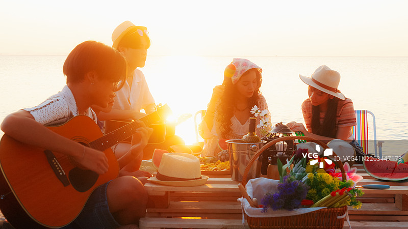 一群朋友在海滩的篝火派对上愉快地享受时光。图片素材