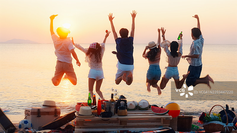 一群朋友在海滩的篝火派对上愉快地享受时光。图片素材