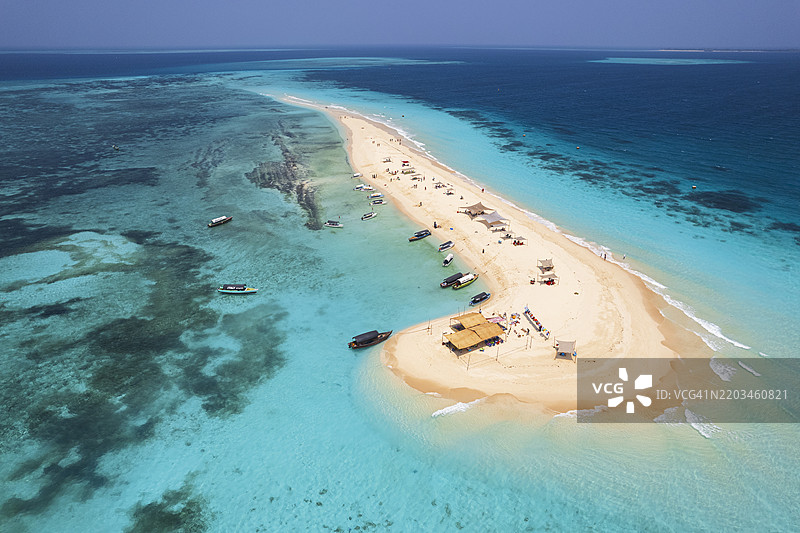 停泊在沙漠岛屿晶莹海水中的船只图片素材