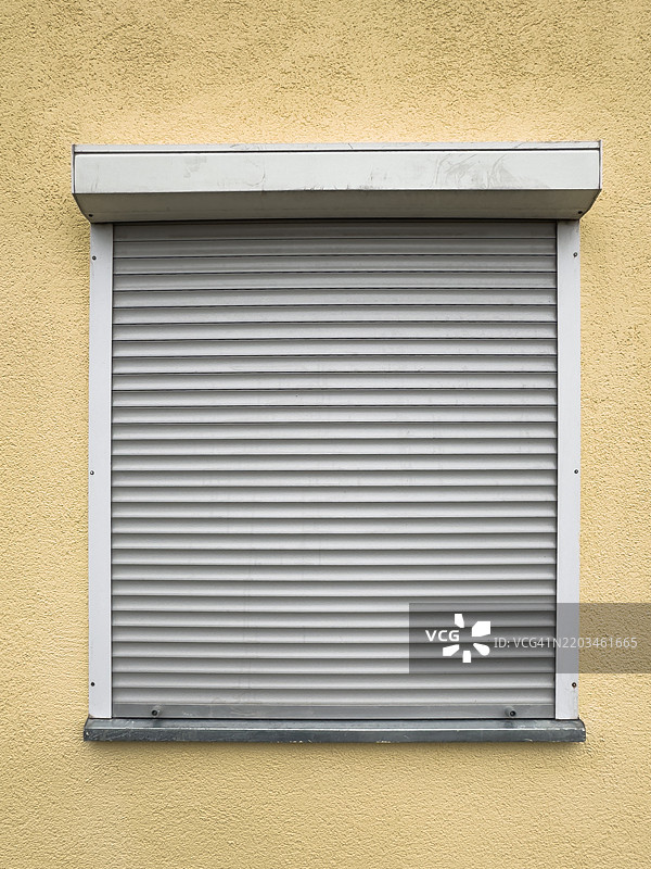 黄色墙壁上的闭合百叶窗图片素材