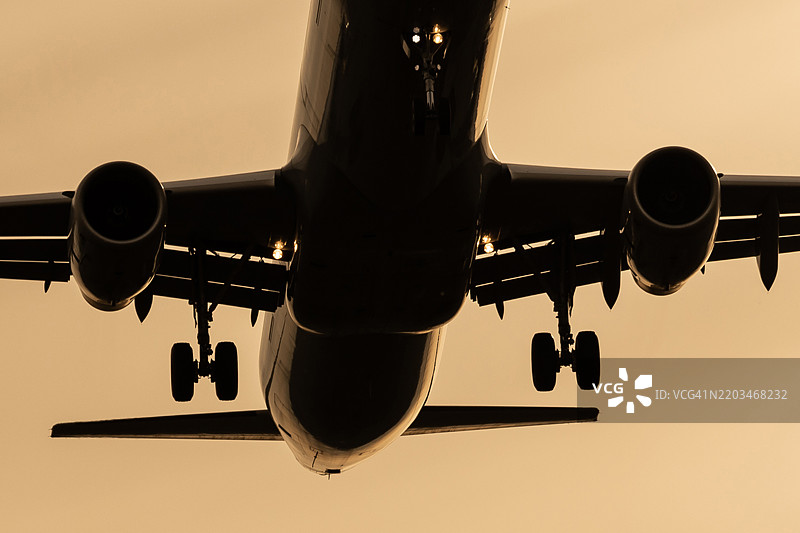 日落时分，接近的飞机的起落架和涡轮发动机图片素材