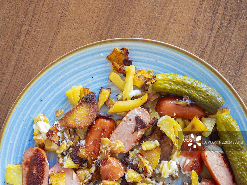 享受一盘美味的脆炸土豆，搭配香肠和清爽的黄瓜卷图片素材