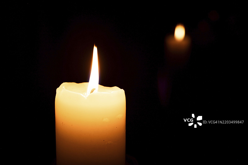 黑暗中点燃的蜡烛及其在背景中的倒影图片素材