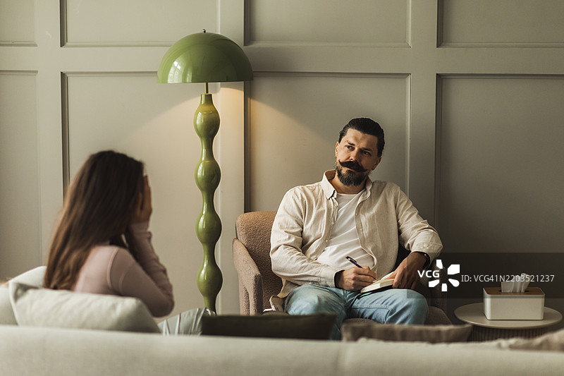 在舒适的办公室环境中，治疗师与客户的咨询会话图片素材