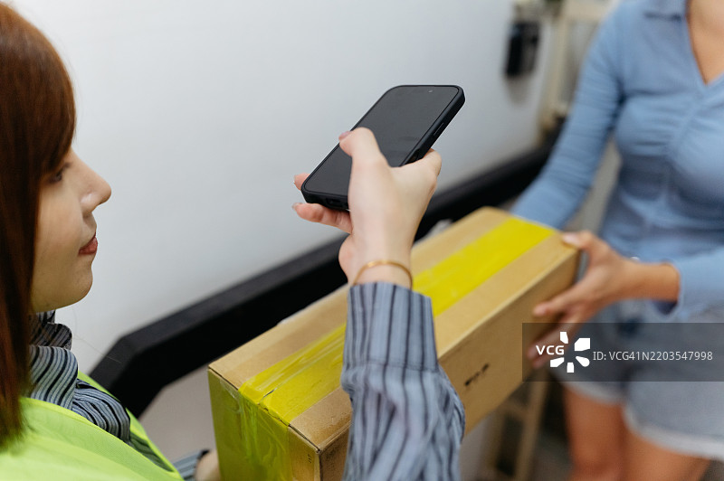 亚洲女性快递员在前门向一位女性递送包裹图片素材