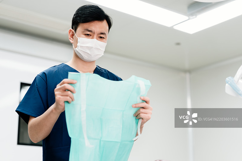 亚洲男性牙医在牙科手术室内做准备。诊所或医院概念。图片素材