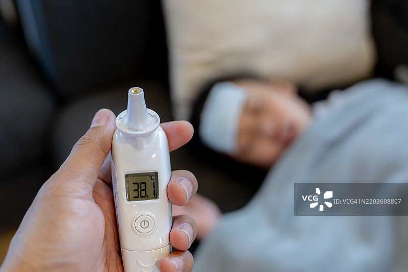 母亲用电子温度计给生病的女儿测量体温图片素材
