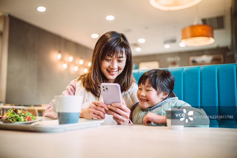 母女在咖啡馆用智能手机分享欢笑图片素材