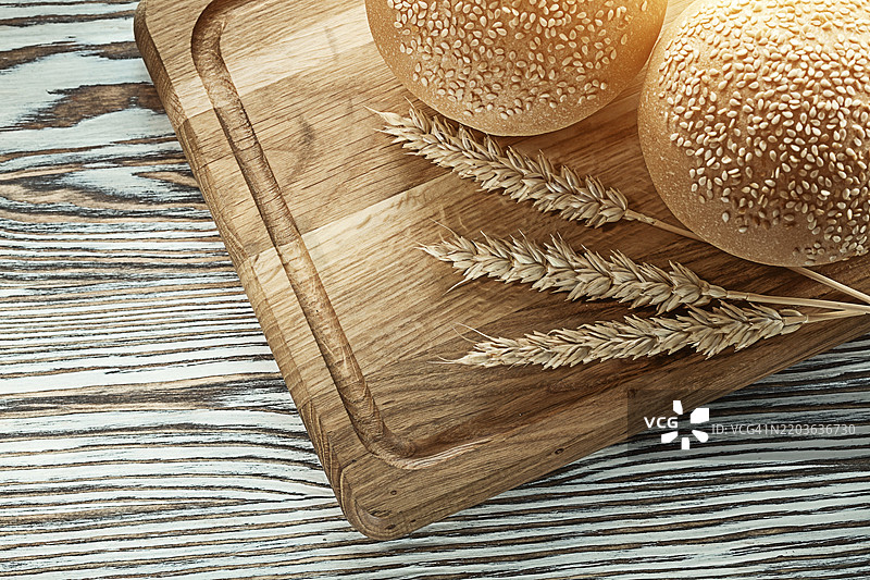 切菜板上的面包和麦穗放在木质表面上图片素材