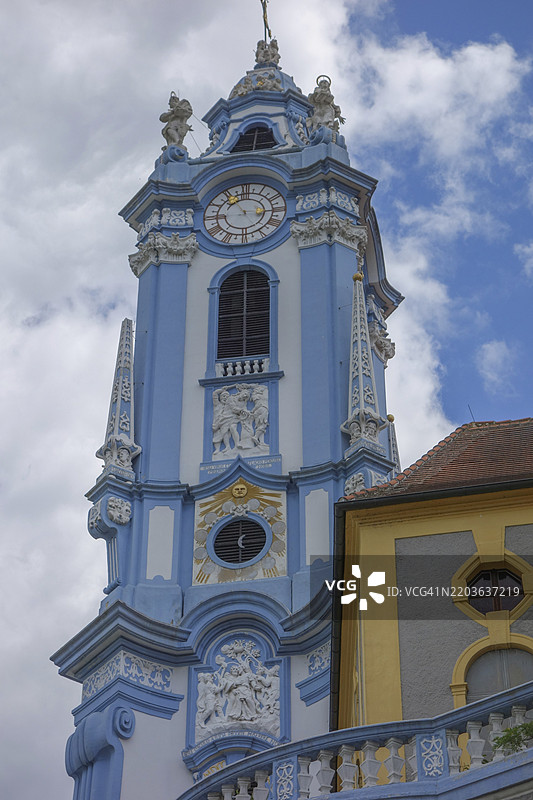 巴洛克风格的教堂塔楼，带有时钟和丰富装饰的蓝色和黄色建筑，位于奥地利多瑙河的瓦豪地区。图片素材
