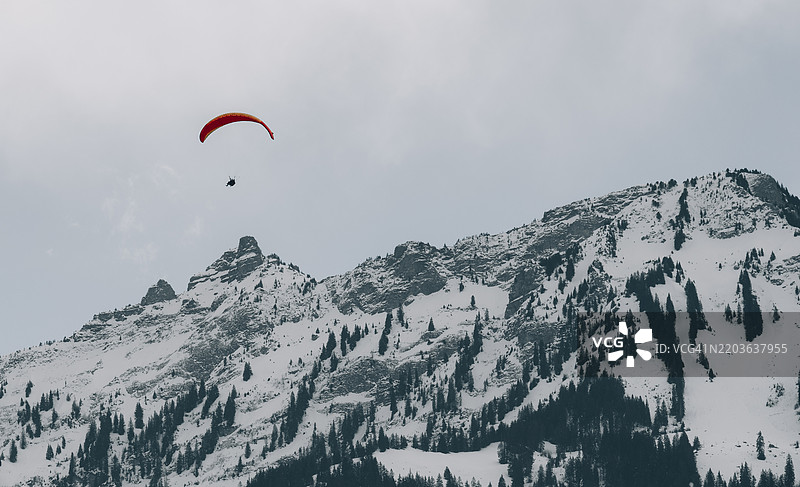 低角度视图的人在天空中滑翔伞飞行图片素材