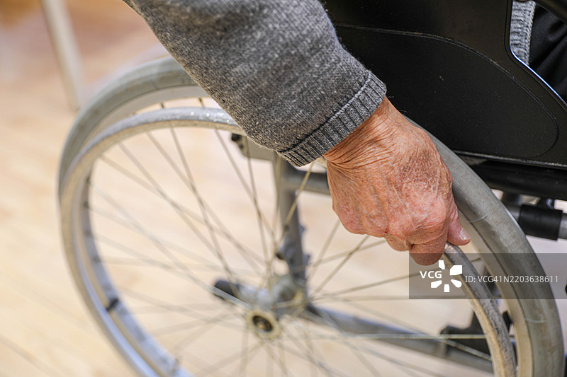 特写镜头：老年人手握轮椅轮子，象征着流动性和独立性图片素材