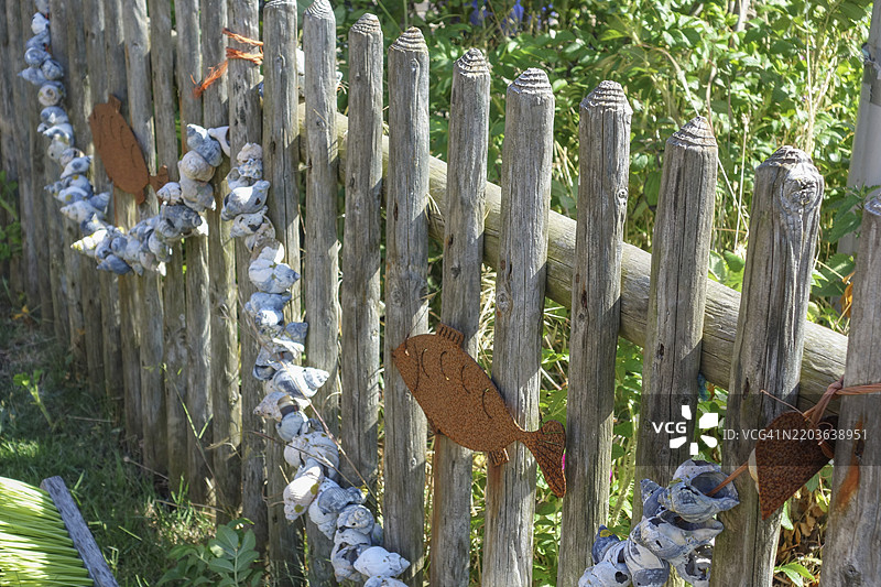 乡村风格的围栏，装饰有贝壳和鱼的挂饰链，位于德国奥斯特弗里斯兰。图片素材