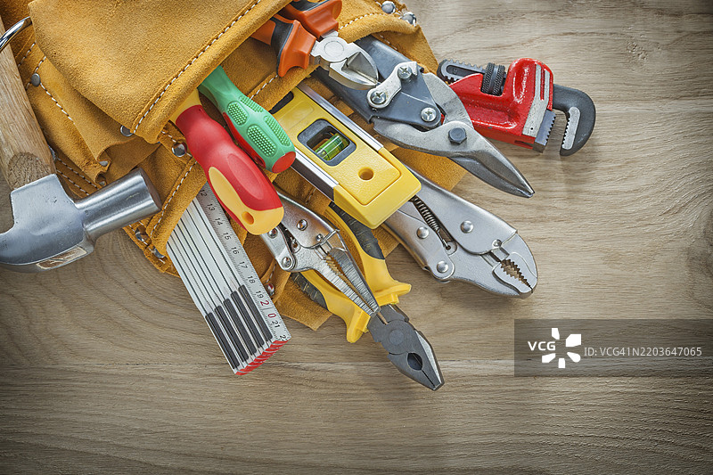 木板上的皮革工具带里的建筑工具图片素材