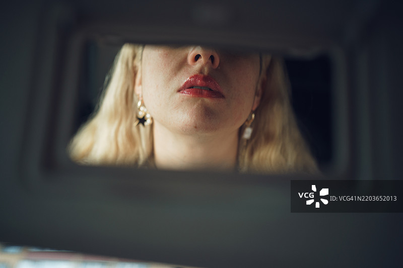 女人在车镜中检查她的红色口红图片素材