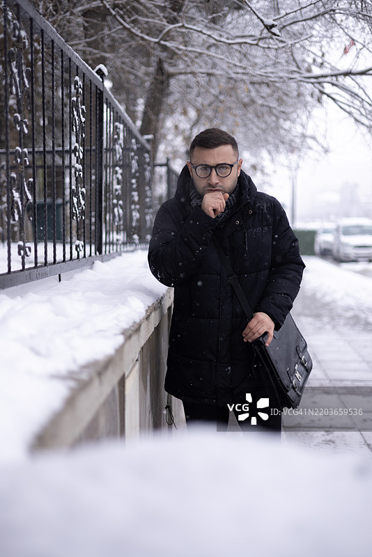 在寒冷的雪天，公园里一个生病的男人在咳嗽图片素材