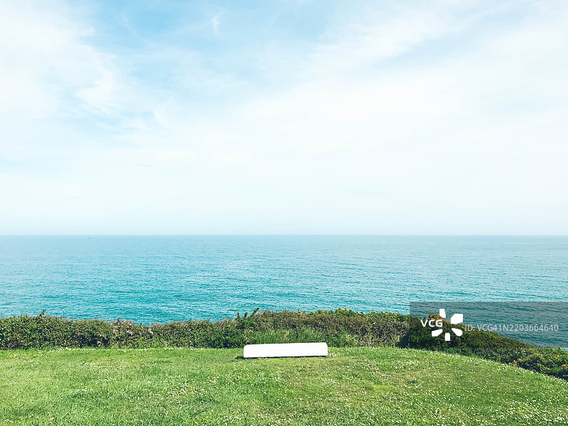 海边草地上的白色长椅图片素材
