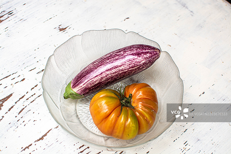 新鲜蔬菜放在乡村风格的白色桌子上：茄子和西红柿图片素材