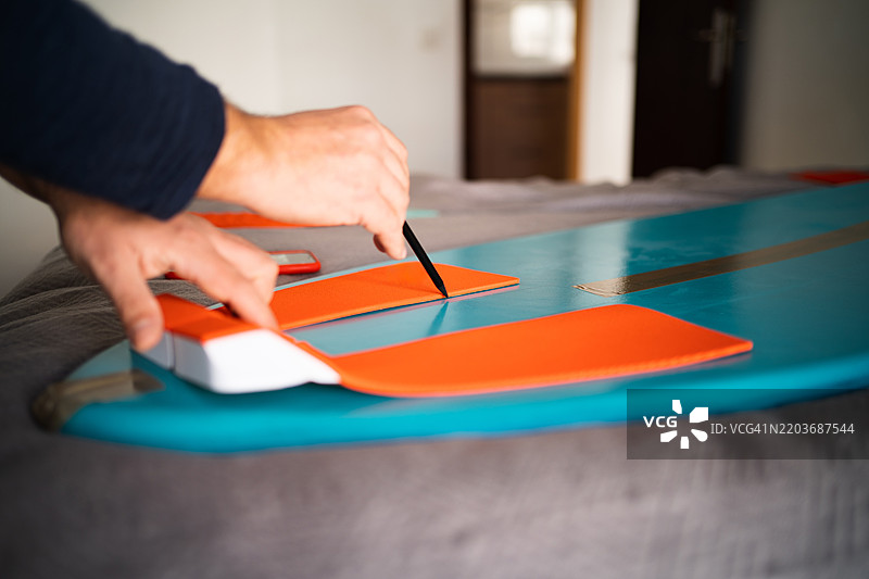 男子精准地将抓握垫贴在滑水板上图片素材