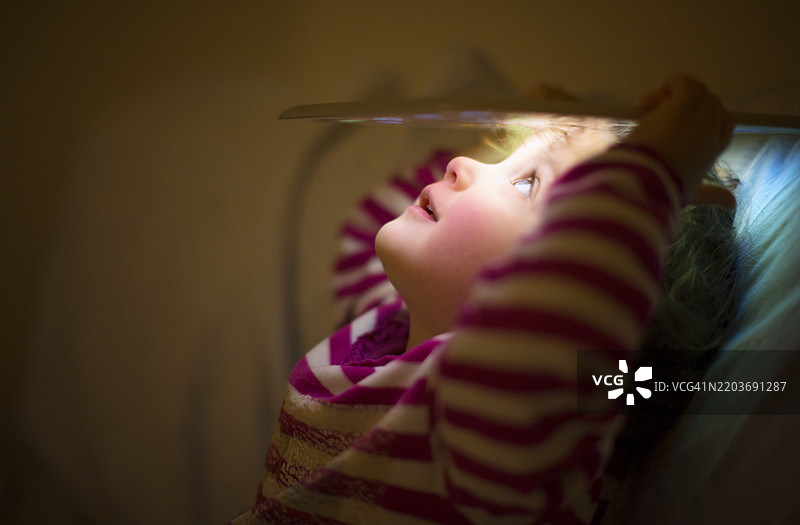 小女孩在床上用毯子探索数字平板电脑图片素材