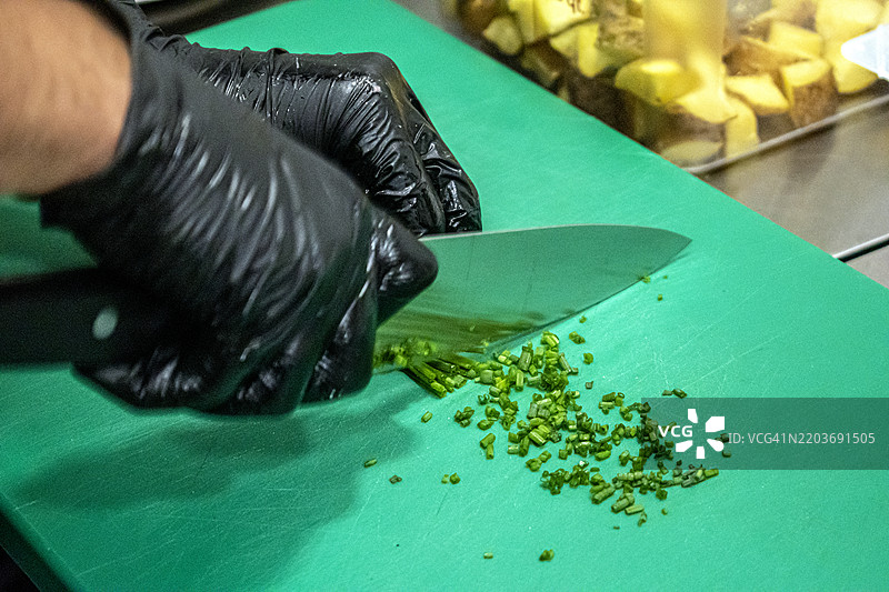 男子在切碎香菜、芹菜和香葱。图片素材