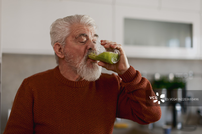 退休老人正在家中制作水果和蔬菜奶昔图片素材