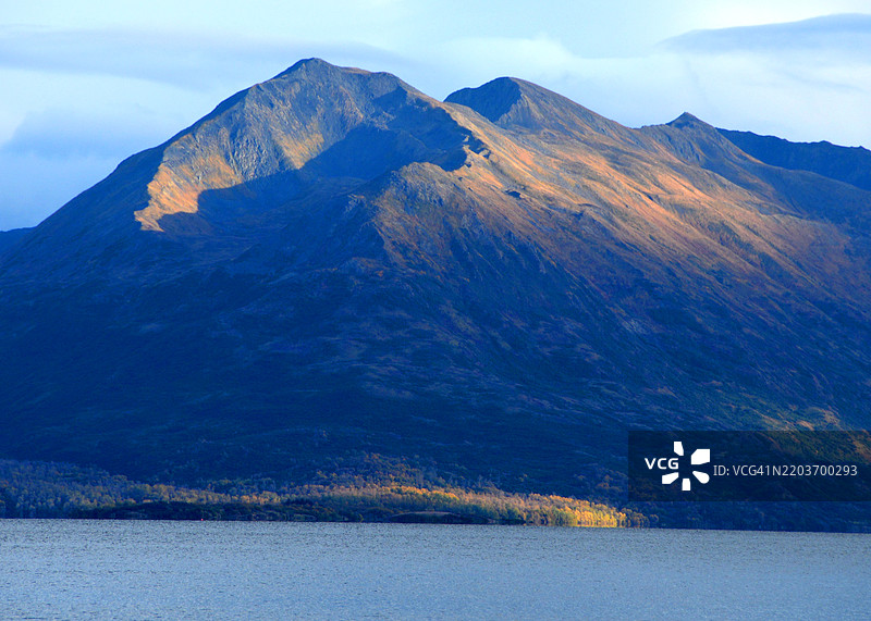 阿拉斯加科迪亚克国家野生动物保护区卡尔鲁克湖上，秋季色彩的山脉沐浴在阳光下。图片素材