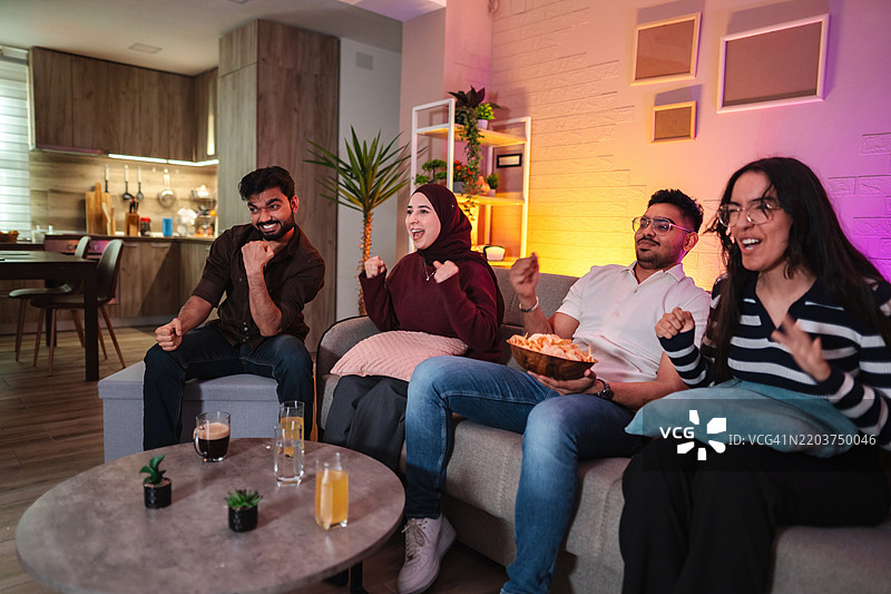 兴奋的朋友们在家看电视时欢呼雀跃图片素材